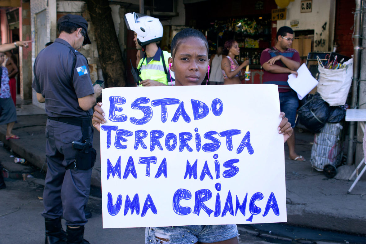 Moradora carrega cartaz denunciando a violência do Estado — Foto Rafael Daguerre
